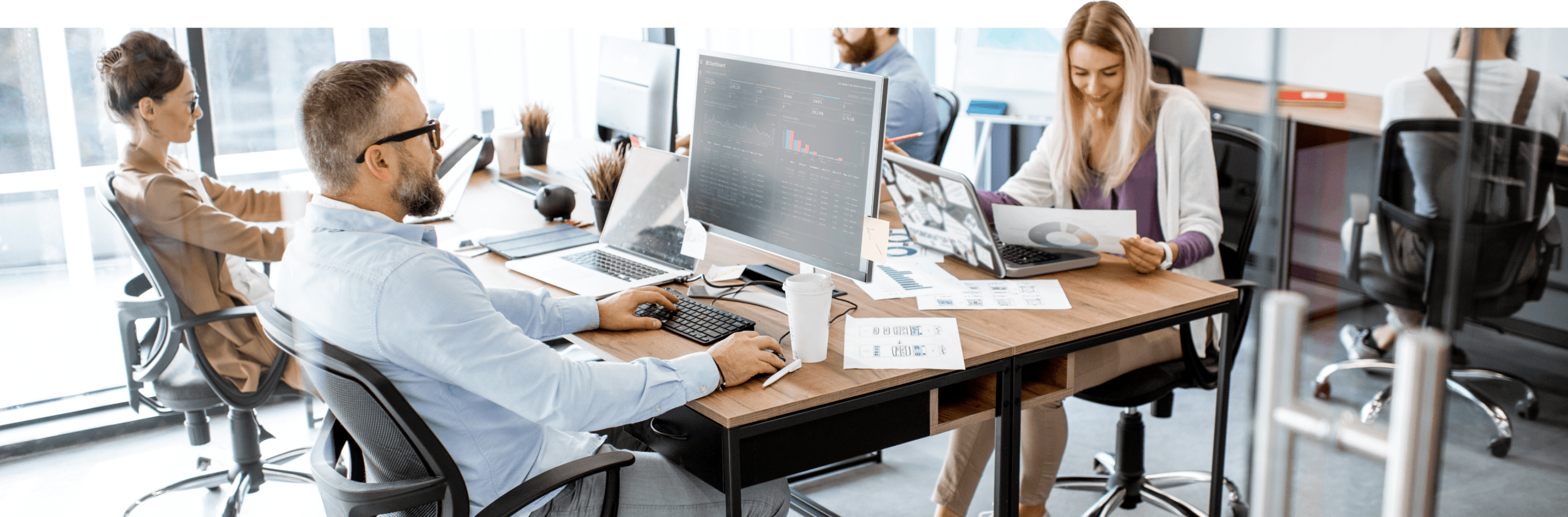 Man types, woman holds paper, busy WordPress Development office.